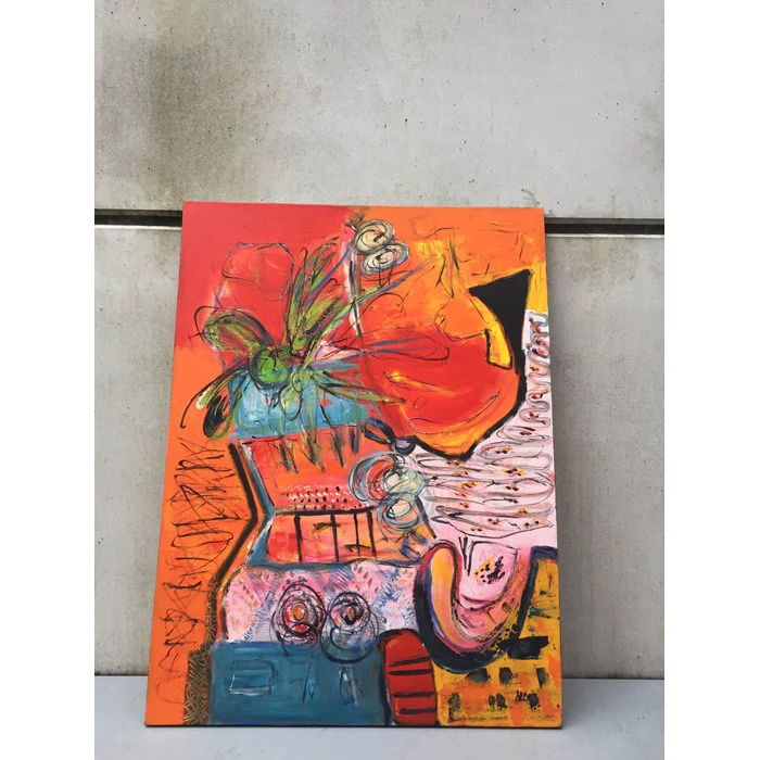 Et farverigt abstrakt maleri med røde, orange og gule toner, med dristige former, kruseduller og hvirvler, der læner sig op ad en betonvæg.